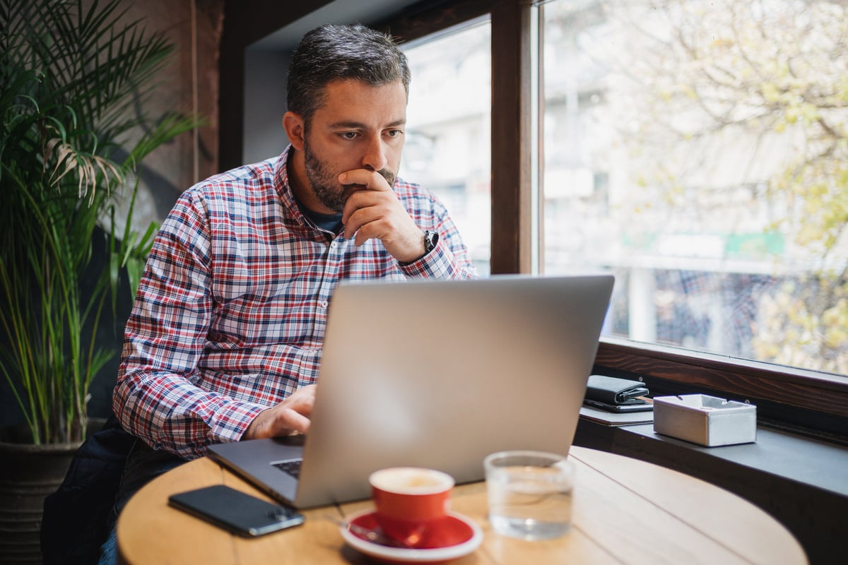Small business owner checking email on computer at cafeteria.